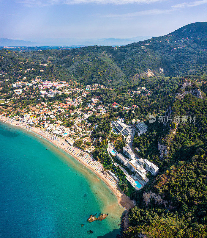 希腊科孚岛的Agios Gordios海滩。希腊科孚岛的Agios Gordios海滩。Agios Gordios海滩的全景，沙滩上有沙滩伞和躺椅。